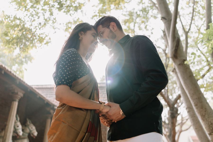 A couple standing forehead to forehead beneath trees