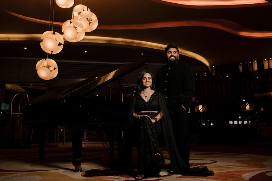A couple in a darkened lounge beside a piano