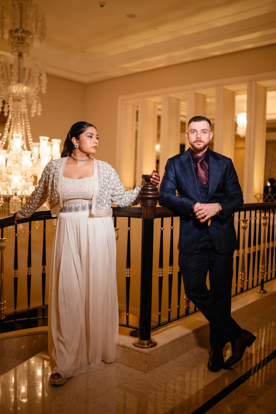 A couple on a staircase beneath a chandelier